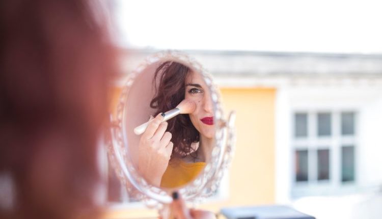 Donna che si sta truccando secondo le tendenze make-up dell’estate 2025