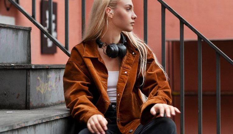 Giovane ragazza seduta su una scala, che indossa abbigliamento da Street style