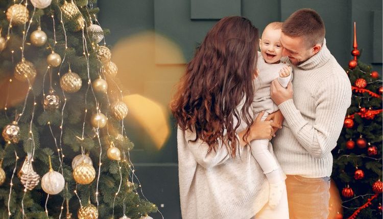 Famiglia vicino albero di Natale, con outfit coordinati con tonalità beige